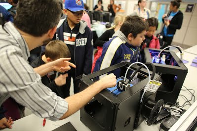 Isaac shows the children how a 3D printer works